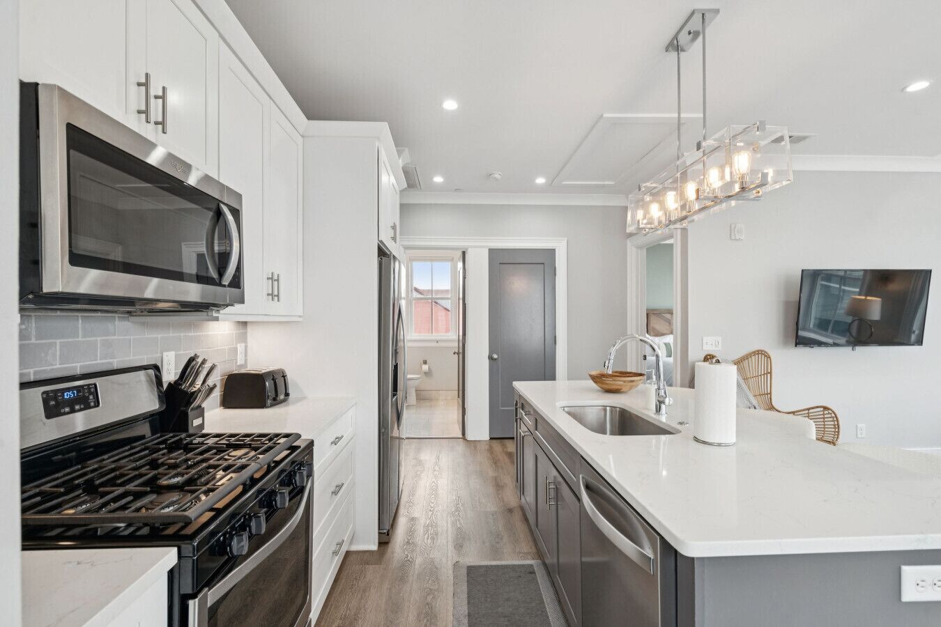 A modern kitchen with stainless steel appliances, a large island with a sink, and a dining area with a TV.