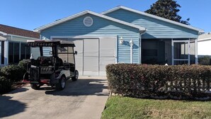 Une maison d’habitation avec un garage, une pelouse et un véhicule de golf garé devant.