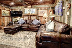 A rustic living room with leather sofas, a flat-screen TV, and vintage decor. - River Bungalow on the Colorado River 2 Miles From Historic Bastrop, Texas (Bastrop)