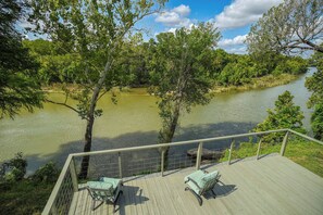 Eine Terrasse mit zwei Schaukelstühlen mit Blick auf einen Fluss.