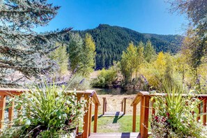 Surrounded by lush greenery and a serene forested backdrop, this deck offers a tranquil view of the river.