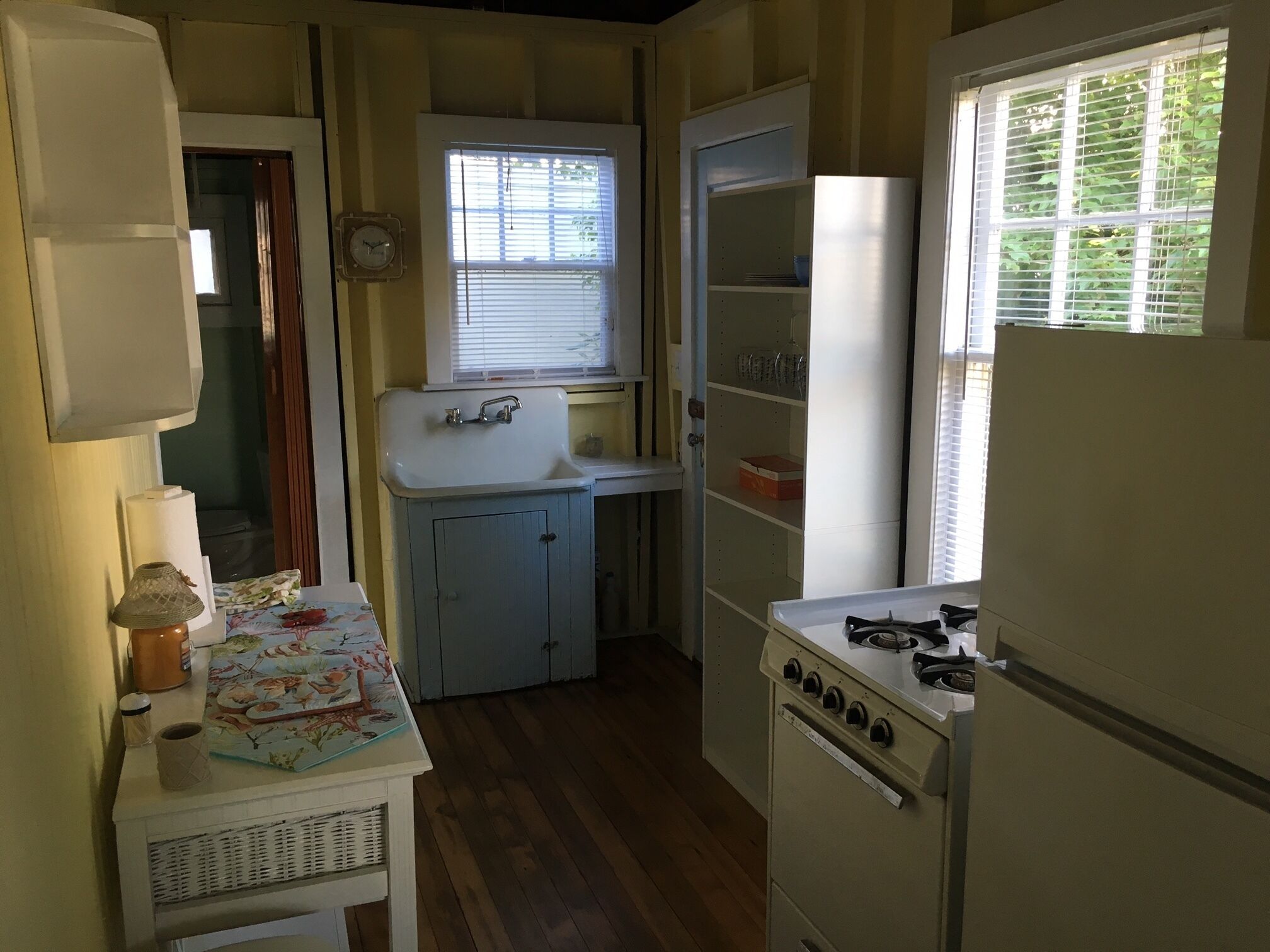 A compact kitchen with a sink, stove, and a small table with a mat.