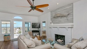 A spacious living room with a fireplace, a ceiling fan, and a television. - Relaxed Cancellation Policy! Oceanfront home with pool,hot tub, fire pit, bikes. (St Augustine)