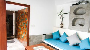 Een moderne woonkamer met een blauwe bank, een houten salontafel en een kleurrijk abstracte wand.