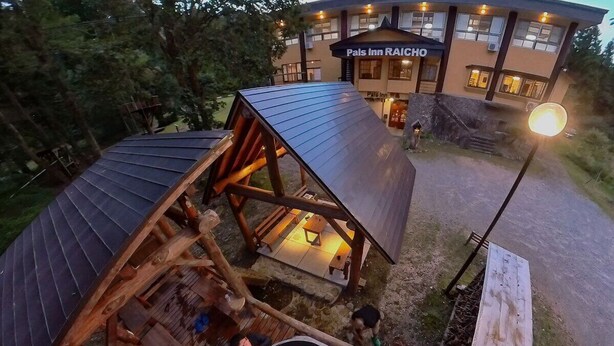 Una cabaña de madera con jacuzzi y terraza, rodeada de árboles.