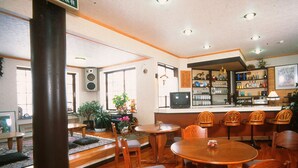 Un restaurante con mobiliario de madera, una zona de bar y un pilar grande.