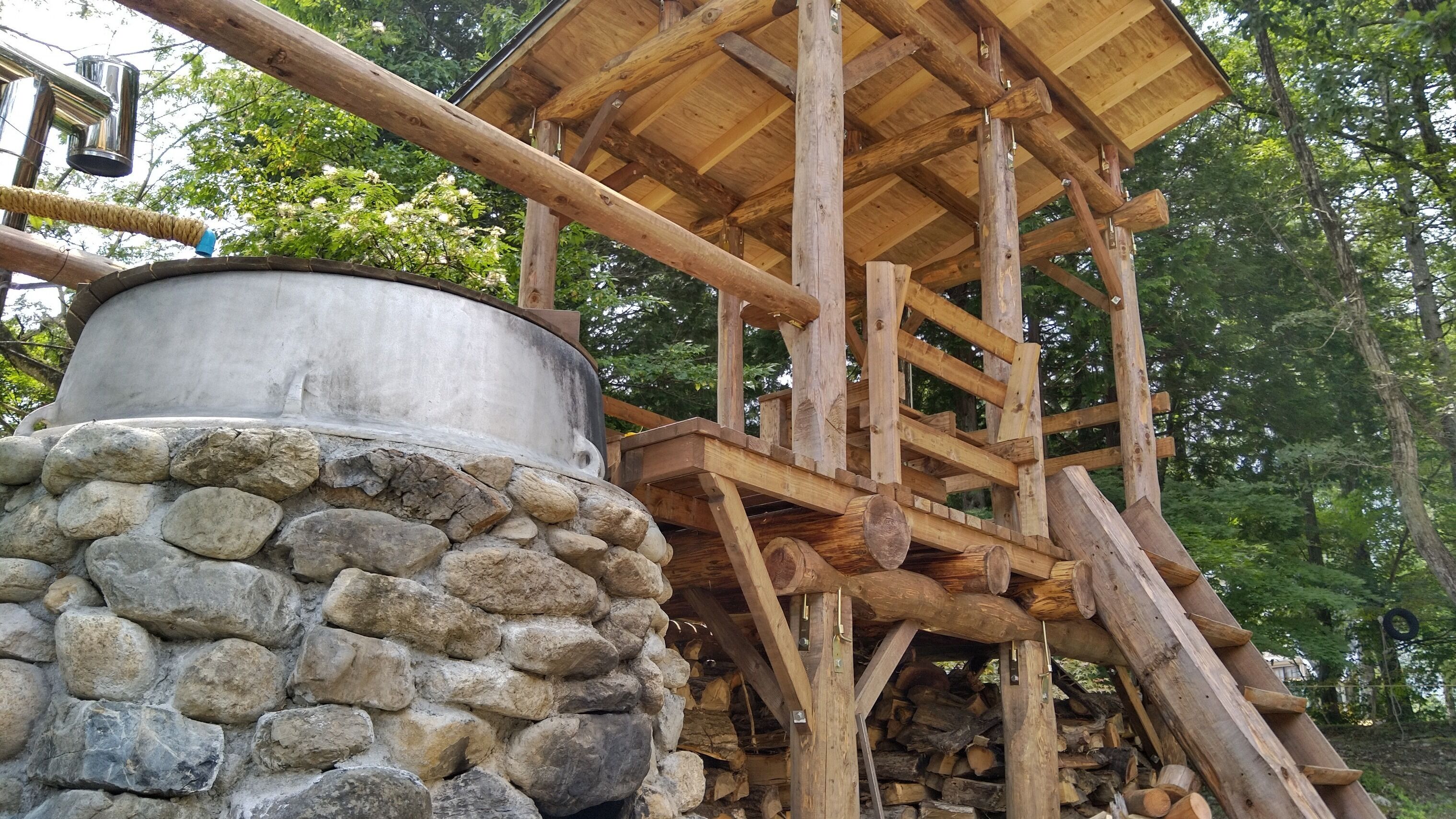 A rustic wooden structure with a stone base and a metal tank.