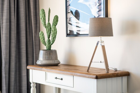 A desk with a potted cactus, a lamp, and a framed artwork on the wall. - Ocean views 27 (Airlie Beach)