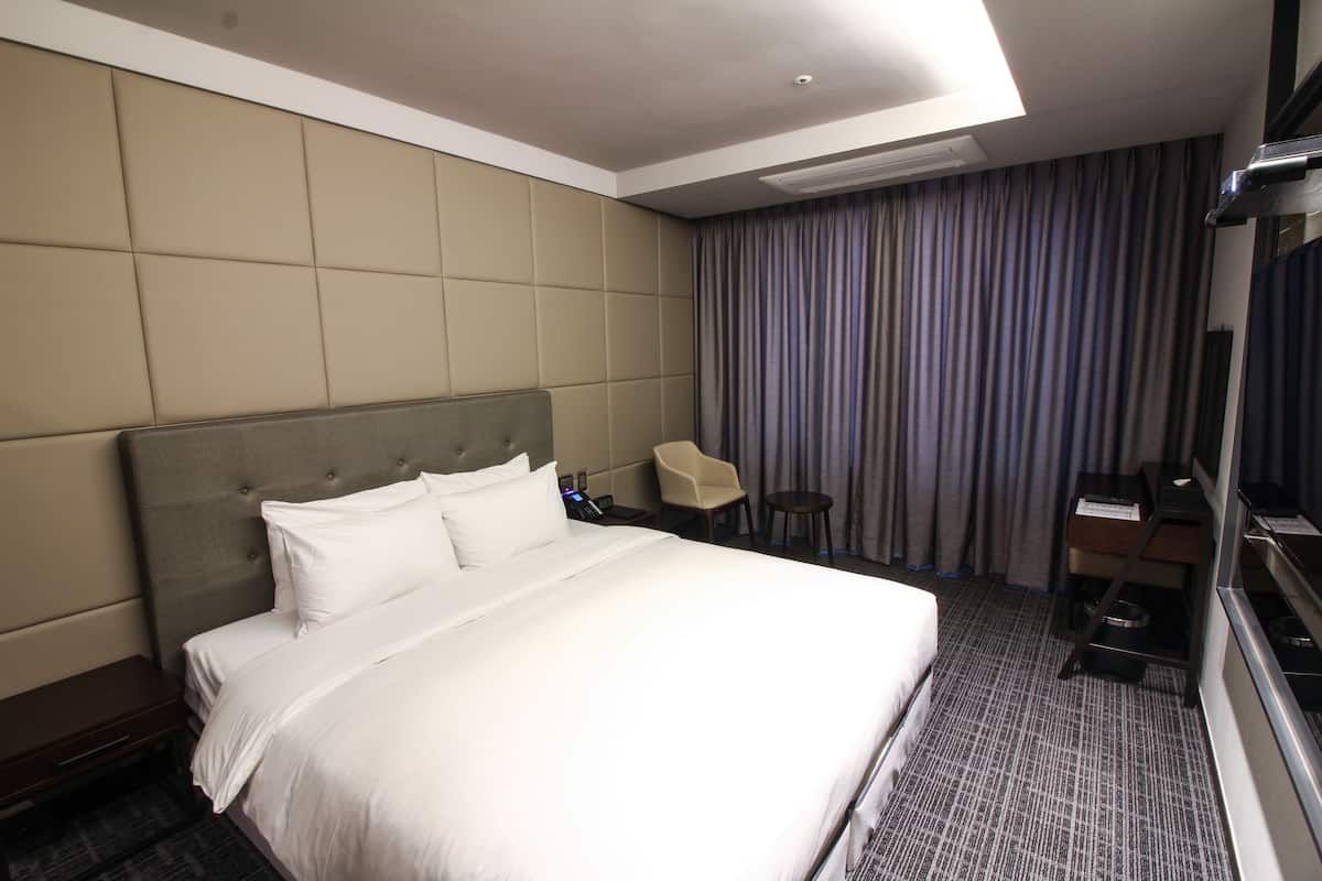 A hotel room with a large bed, a small table, a chair, and a TV.