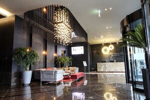 Un vestíbulo moderno con mostrador de recepción, zona de estar e iluminación decorativa.