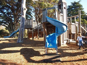 Une aire de jeux avec un toboggan bleu et des structures en bois.
