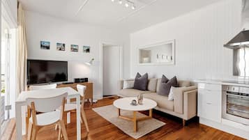A modern living room with a television, sofa, coffee table, and kitchen area.