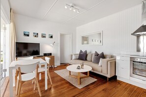 A modern living room with a television, sofa, coffee table, and kitchen area.