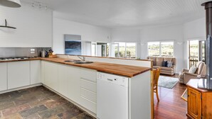 Une cuisine spacieuse dotée d’un plan de travail en bois, de meubles blancs et d’un lave-vaisselle.