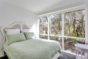 A bedroom with a large window, a white bed, and a wicker chair. - The Heyfield Hideaway Rye - PAY 2, STAY 3 Nights! (RYE)