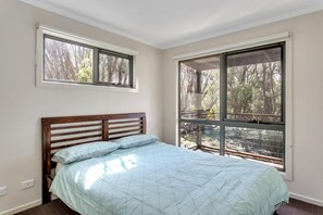 A bedroom with a bed, two windows, and a view of trees. - The Heyfield Hideaway Rye (RYE)