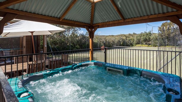 A hot tub under a covered area with a view of the surrounding landscape. - The Heyfield Hideaway Rye (RYE)