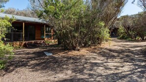 A cabin with a porch, surrounded by trees and a dirt path. - The Heyfield Hideaway Rye (RYE)