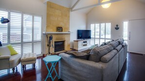 Una sala de estar con chimenea, sofá, televisor y ventilador de techo.