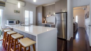 Una cocina moderna con una isla grande, electrodomésticos de acero inoxidable y taburetes de madera.