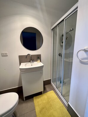 A bathroom with a white sink, a mirror, a toilet, and a glass shower enclosure. - Cozy, Pet Friendly, Family Friendly, Boat Friendly (Rosebud)