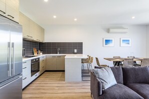 Una cocina moderna con una isla central, taburetes de bar y un comedor con mesa y sillas.