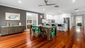 A modern kitchen with white cabinets, a central island, and a dining area with green chairs. - Lady Nelson, Sorrento - hot tub. (SORRENTO)