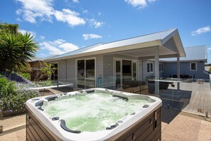 Un jacuzzi en un patio trasero, con una casa al fondo.