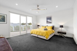 Un dormitorio con cama, ventilador de techo, mesita de noche y vistas al exterior.