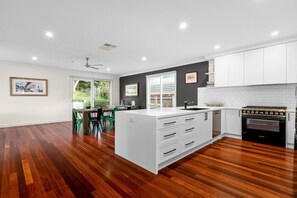 Una cocina moderna con muebles blancos, una isla central y un horno integrado.