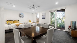 A modern hotel room with a dining area, a bed with yellow pillows, a sofa, a ceiling fan, and a TV. - Lady Nelson, Sorrento - hot tub. (SORRENTO)
