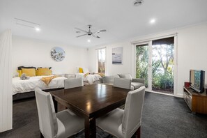 A hotel room with a bed, sofa, dining table, chairs, ceiling fan, artwork, and a TV. - Lady Nelson, Sorrento - hot tub (SORRENTO)