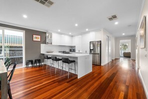 A modern kitchen with a central island, white cabinetry, and a stainless steel refrigerator.