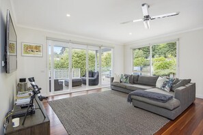 A spacious living room with a grey sectional sofa, a flat-screen TV mounted on the wall, and a telescope on a desk. - Lady Nelson, Sorrento - heated outdoor spa. (SORRENTO)