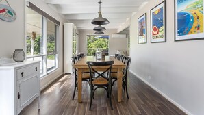 A dining area with a long wooden table, black chairs, and a hanging pendant light.