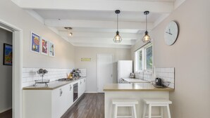 A modern kitchen with white cabinetry, a central island with stools, pendant lighting, and a large window.