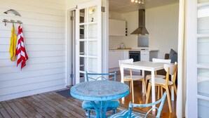 A covered patio with a round table and chairs, a kitchen area with white cabinets, and a number '2' on the door.
