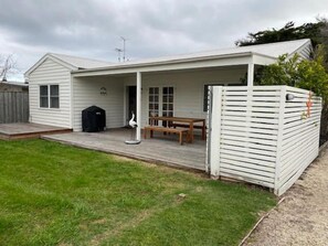 A single-story house with a covered porch, a barbecue grill, and a bench. - Sorrento Beach Cottages #2. (SORRENTO)