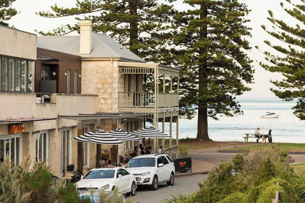 A coastal building with a balcony, outdoor seating, and a view of the sea.
