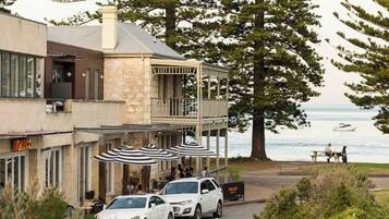 A coastal building with a balcony, outdoor seating, and a view of the sea.