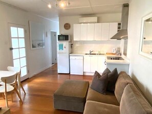 Um espaço compacto com cozinha compacta, sofá, mesa de jantar e uma cadeira.