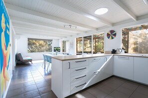 Une cuisine moderne avec des meubles blancs, un grand îlot central et un coin repas avec des chaises.