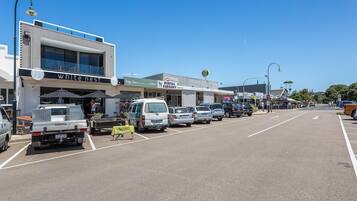 A street view with a row of parked cars, a building with a sign for 'white nest,' and a 'dental surgery' sign.