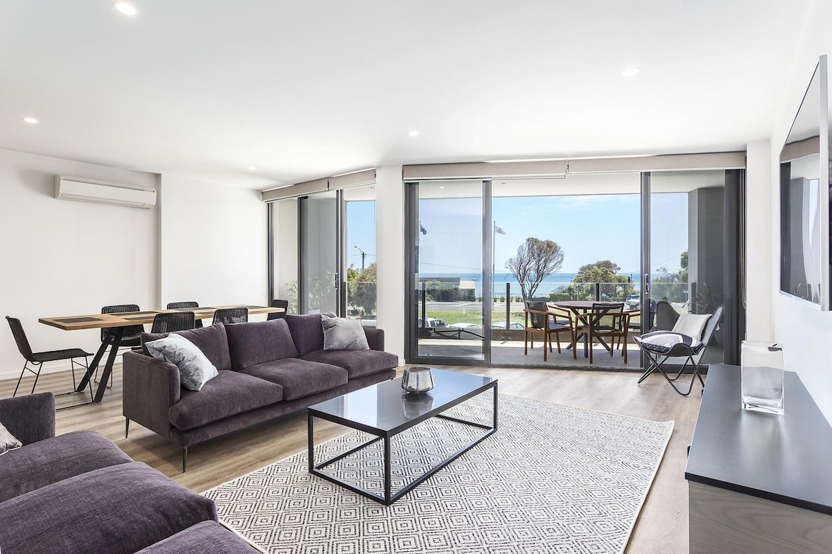 A modern living room with a sofa, coffee table, and dining area.