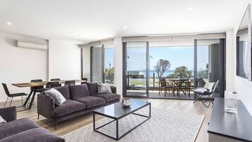 A modern living room with a sofa, coffee table, and dining area.
