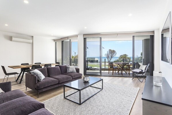 A modern living room with a sofa, coffee table, and dining area.