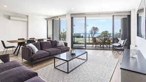 A modern living room with a sofa, coffee table, and dining area.