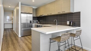 A modern kitchen with a large island, stainless steel appliances, and wooden cabinetry.