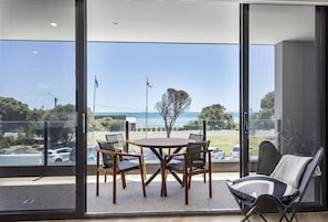 Ein Balkon mit Tisch und Stühlen, Blick aufs Meer und eine Flagge.