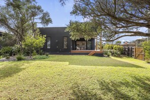 A modern two-story house with a well-maintained lawn and a wooden deck.